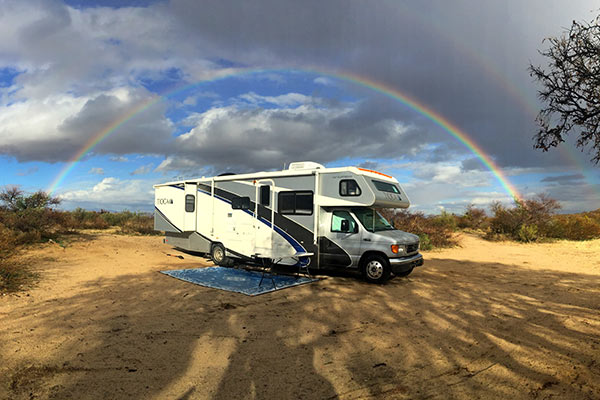RV boondocking beneath a rainbow in the desert