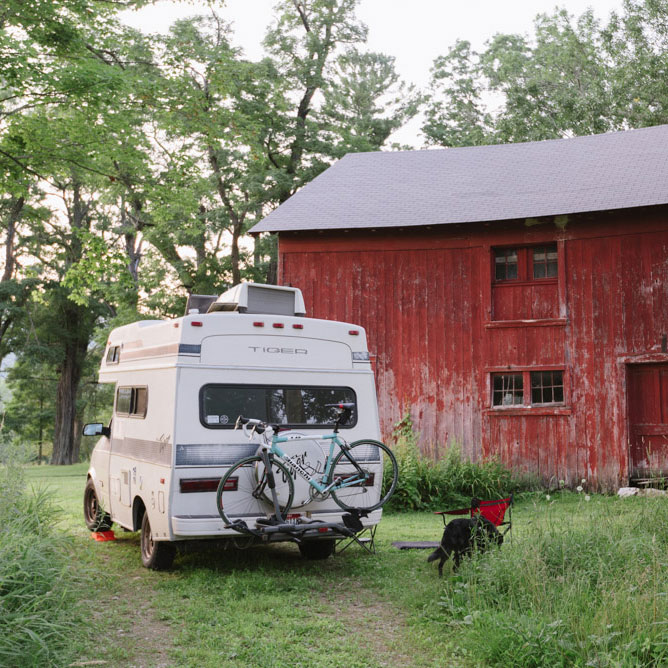 An RV camping by a barn