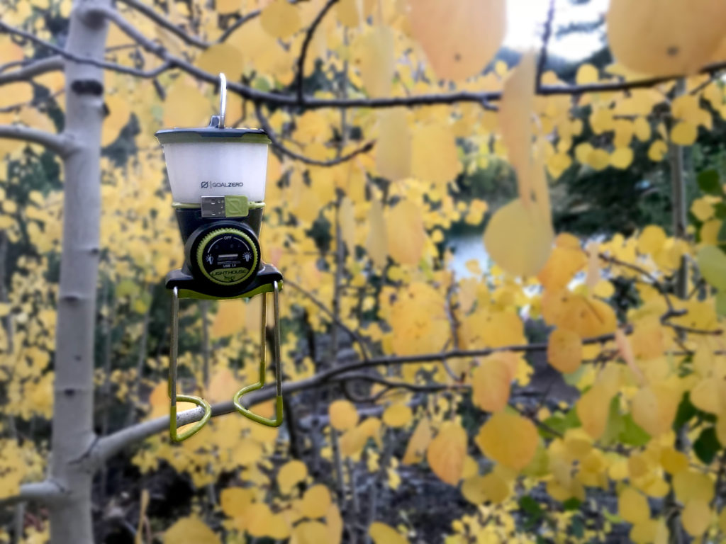 a small camping light hanging from a tree