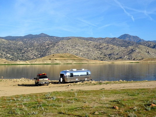 an Airstream parked near a lake in the desert
