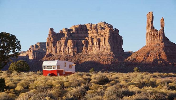 A cute red and white vintage Shasta travel trailer camping for free near a rocky mesa in the United States