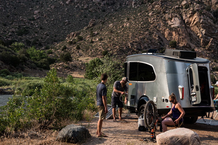 people camping in a small silver travel trailer