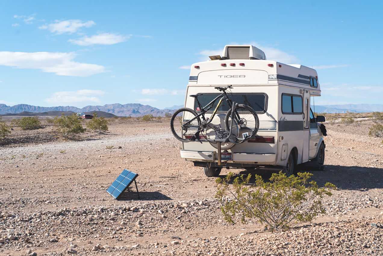 solar panels set up next to a van in the desert