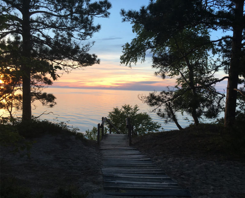 a wooden boardwalk leads to Lake Superior at sunset
