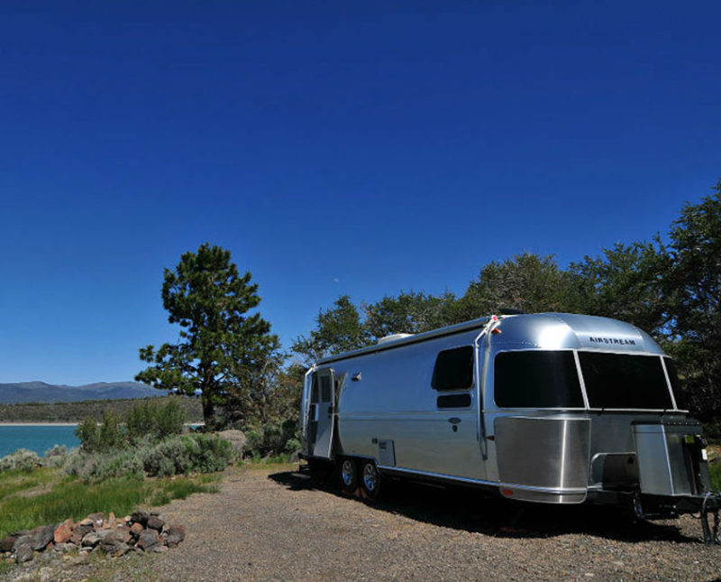 an Airstream travel trailer camping near water and woods