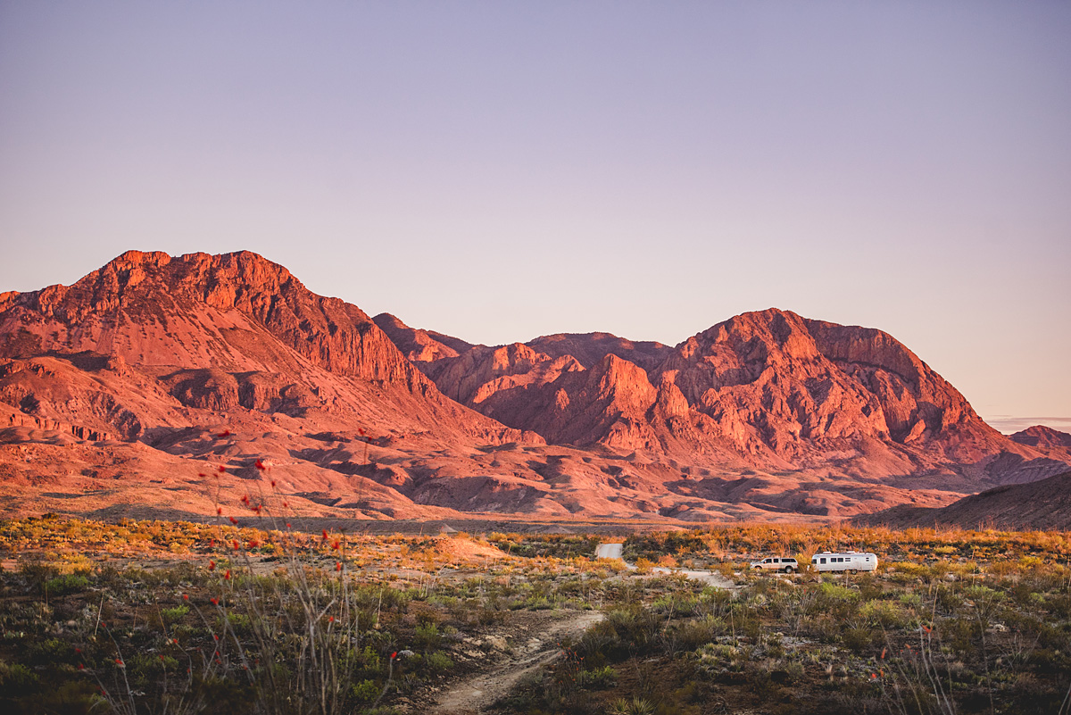 RV parked in a desert landscape at sunset.
