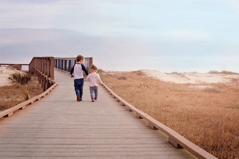 two children walking down the boardwalk at a florida state park