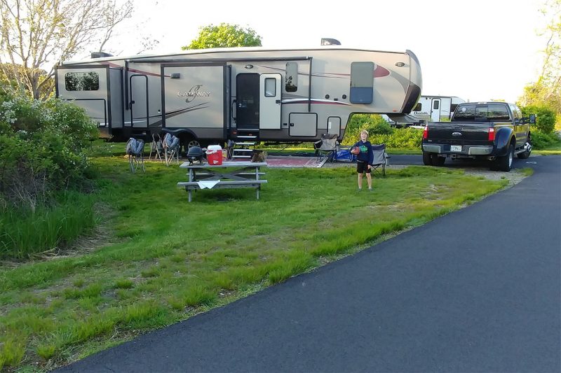 A 5th Wheel camper and a kid playing at a Massachusetts State Park
