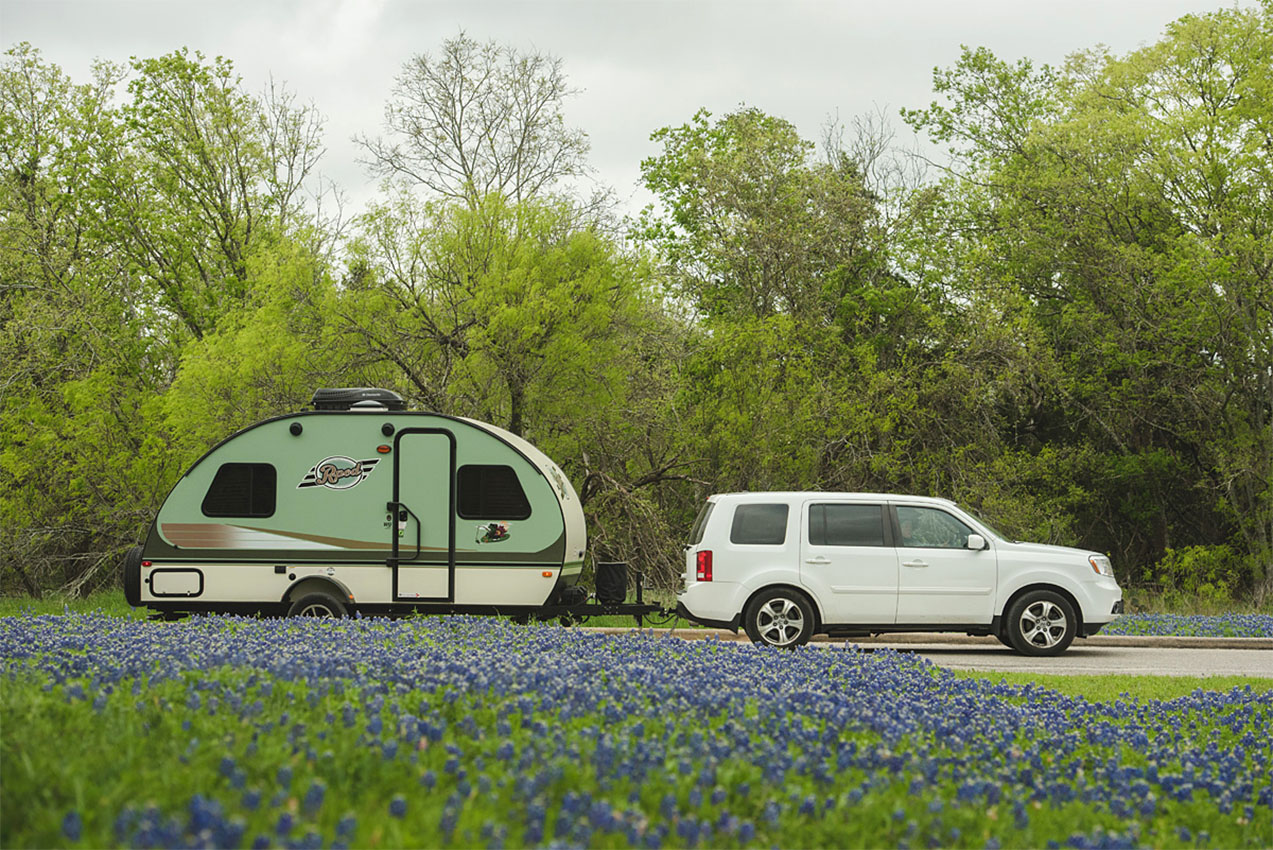A travel trailer next to a field of bluebonnet flowers