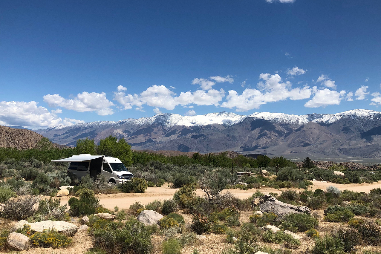 Van camped in front of white capped mountains