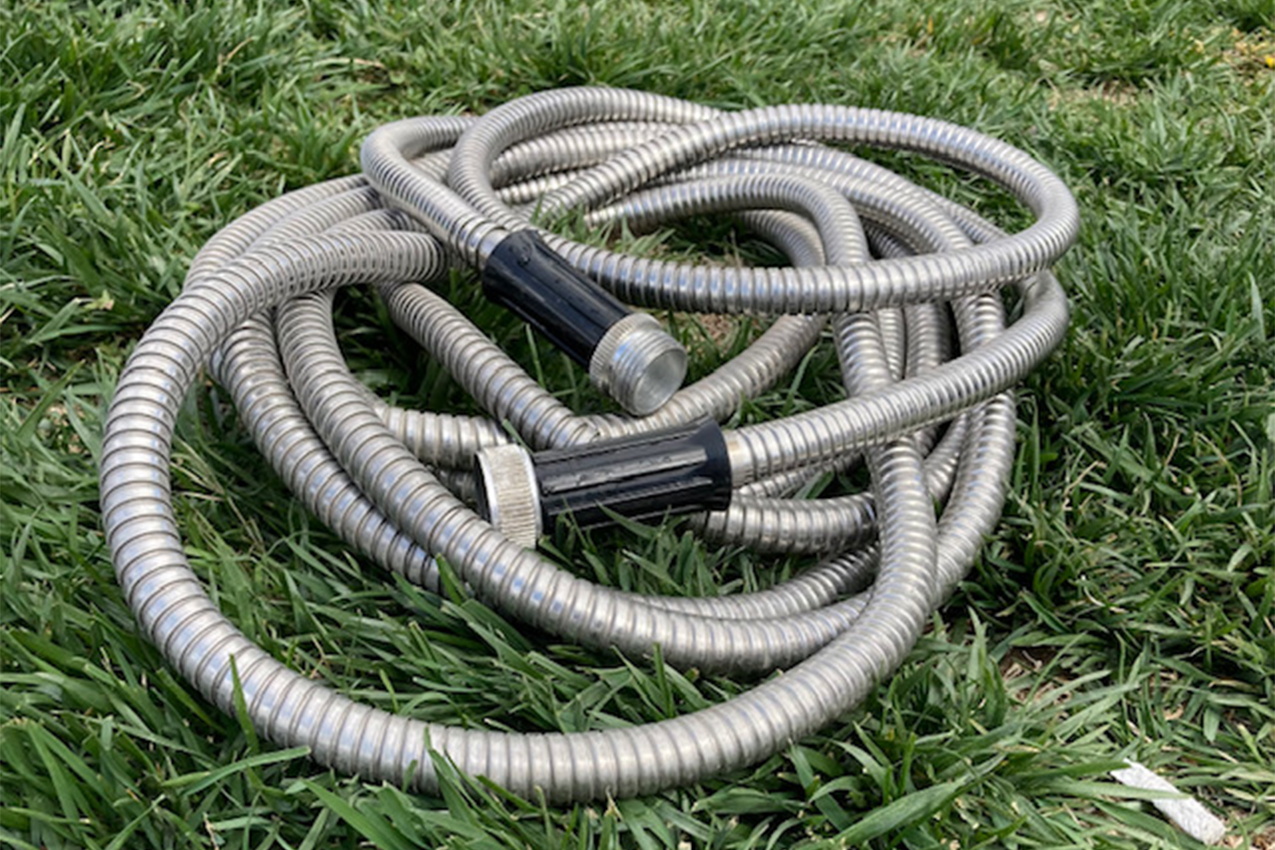 Silver water hose laying on grass.