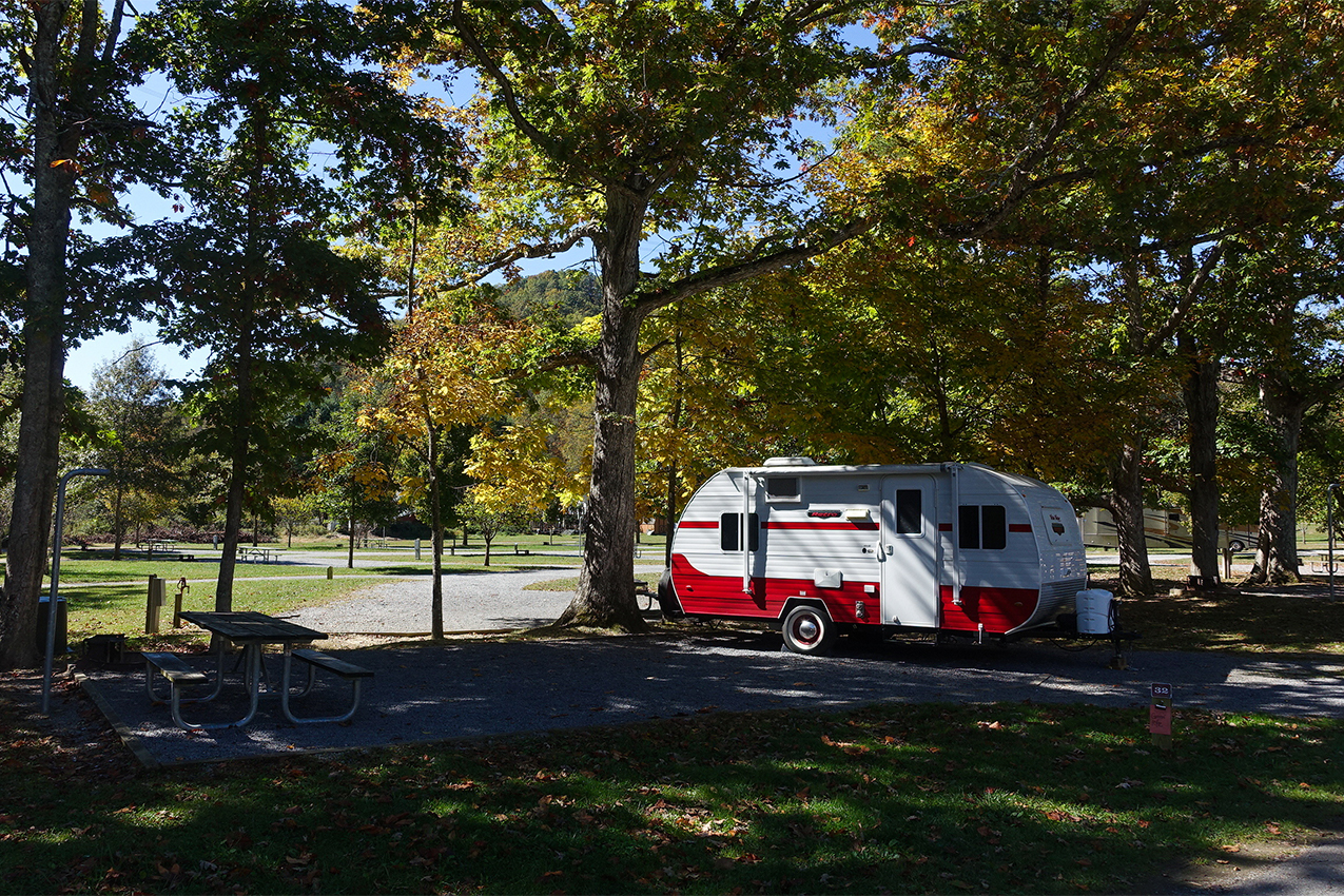 Teardrop camper parked under trees.