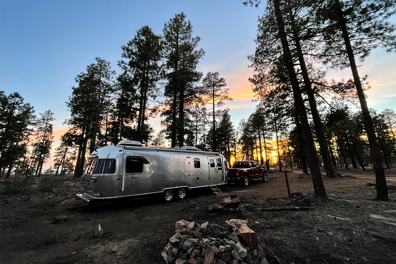 RV parked in the woods at sunset.