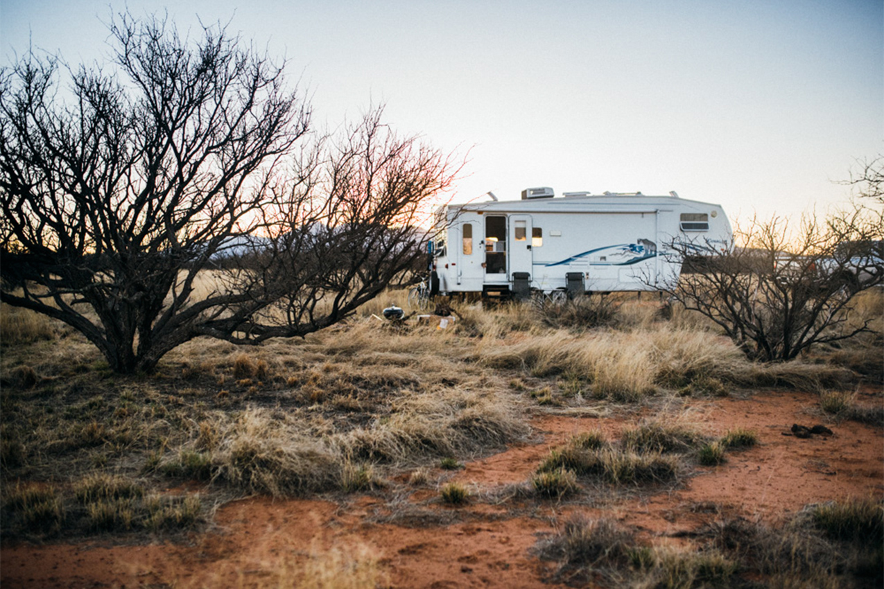 Fifth wheel parked in the desert at sunset.