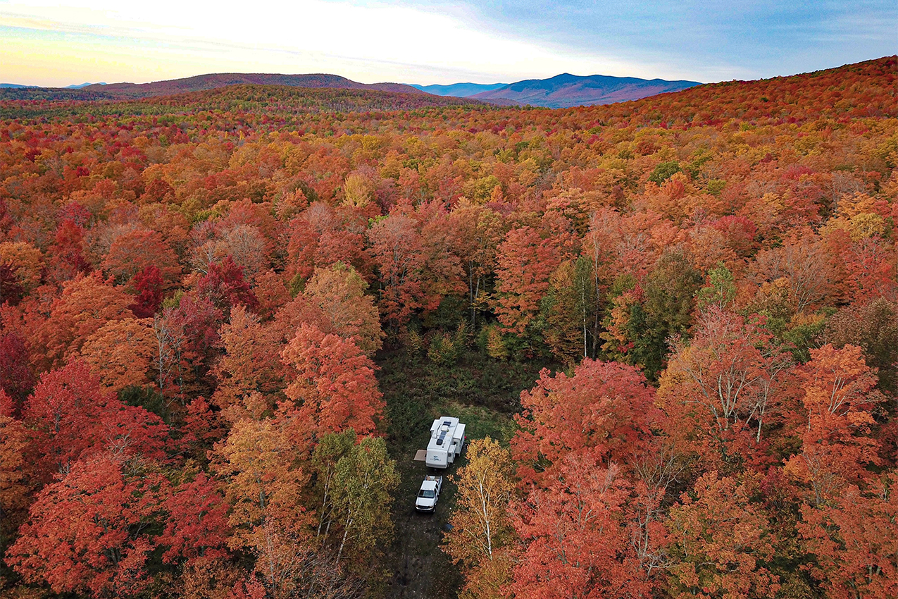RV parked in the middle of a forest with fall colors