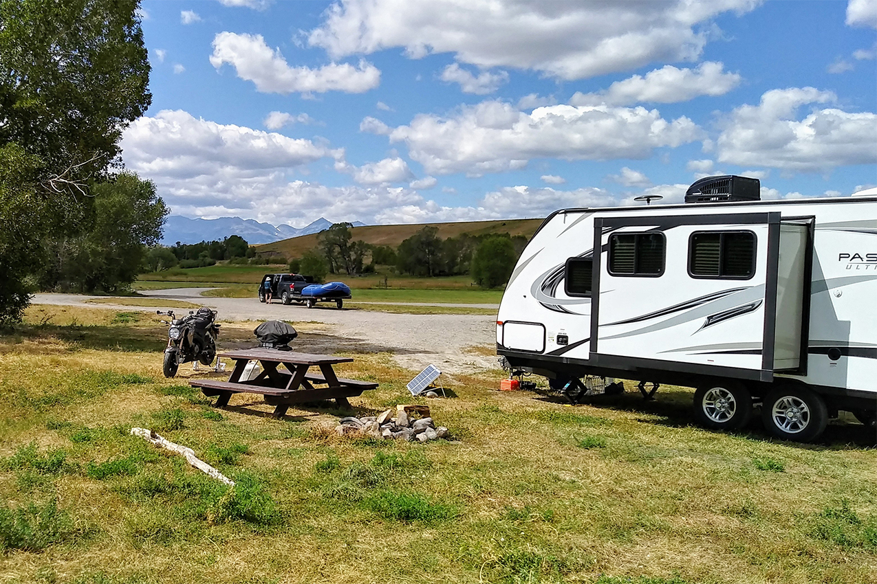 RV parked by a picnic table in a green field.
