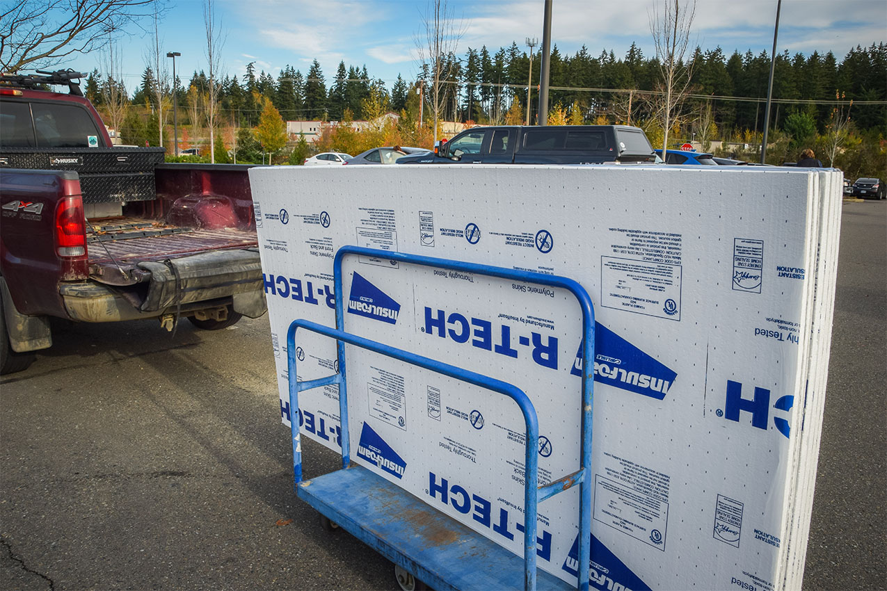 Several large pieces of insulation in a shopping cart behind a truck.