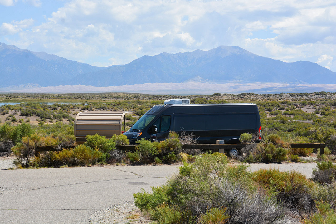 Van parked in a campsite with mountains in the horizon.