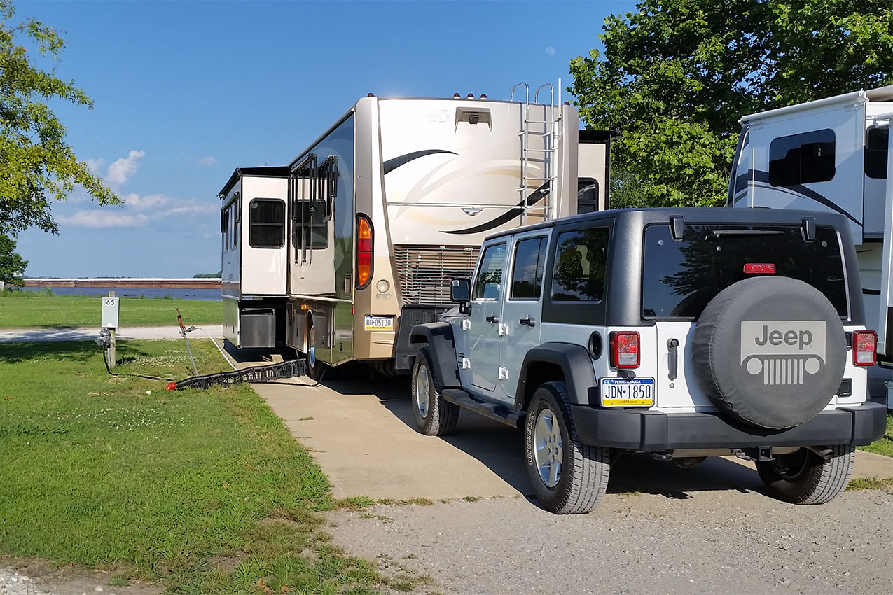 Class A and a Jeep parked in an RV park.