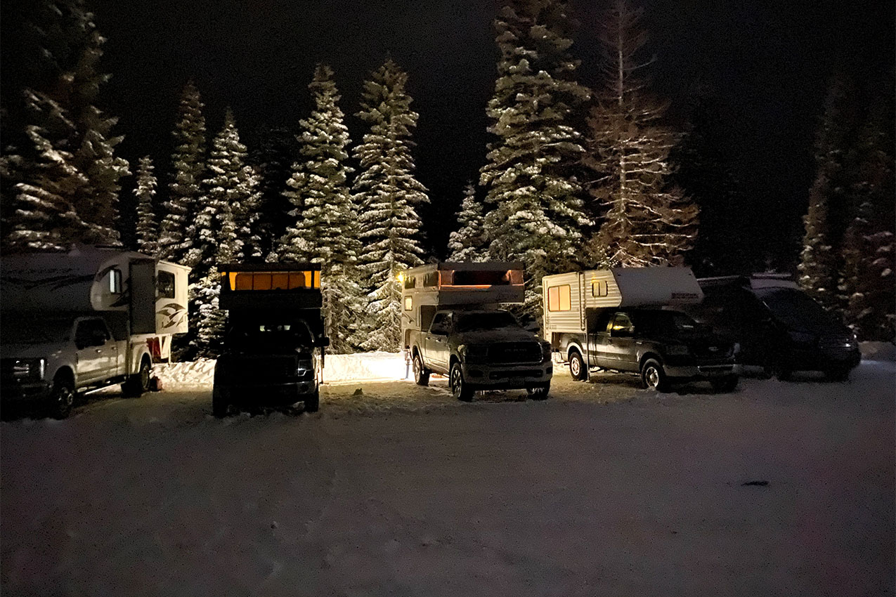RVs parked in a snowy lot at night.