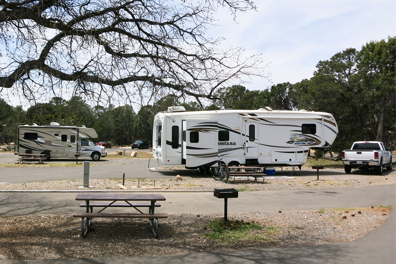 Fifth wheel and truck parked in an RV park next to a class C rig.