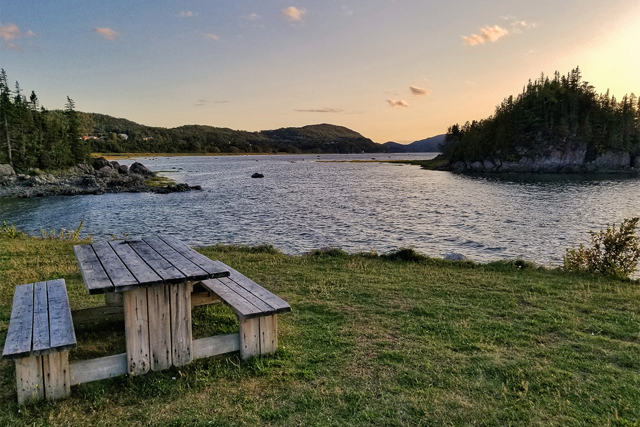 Picnic table in front of a river at sunset.