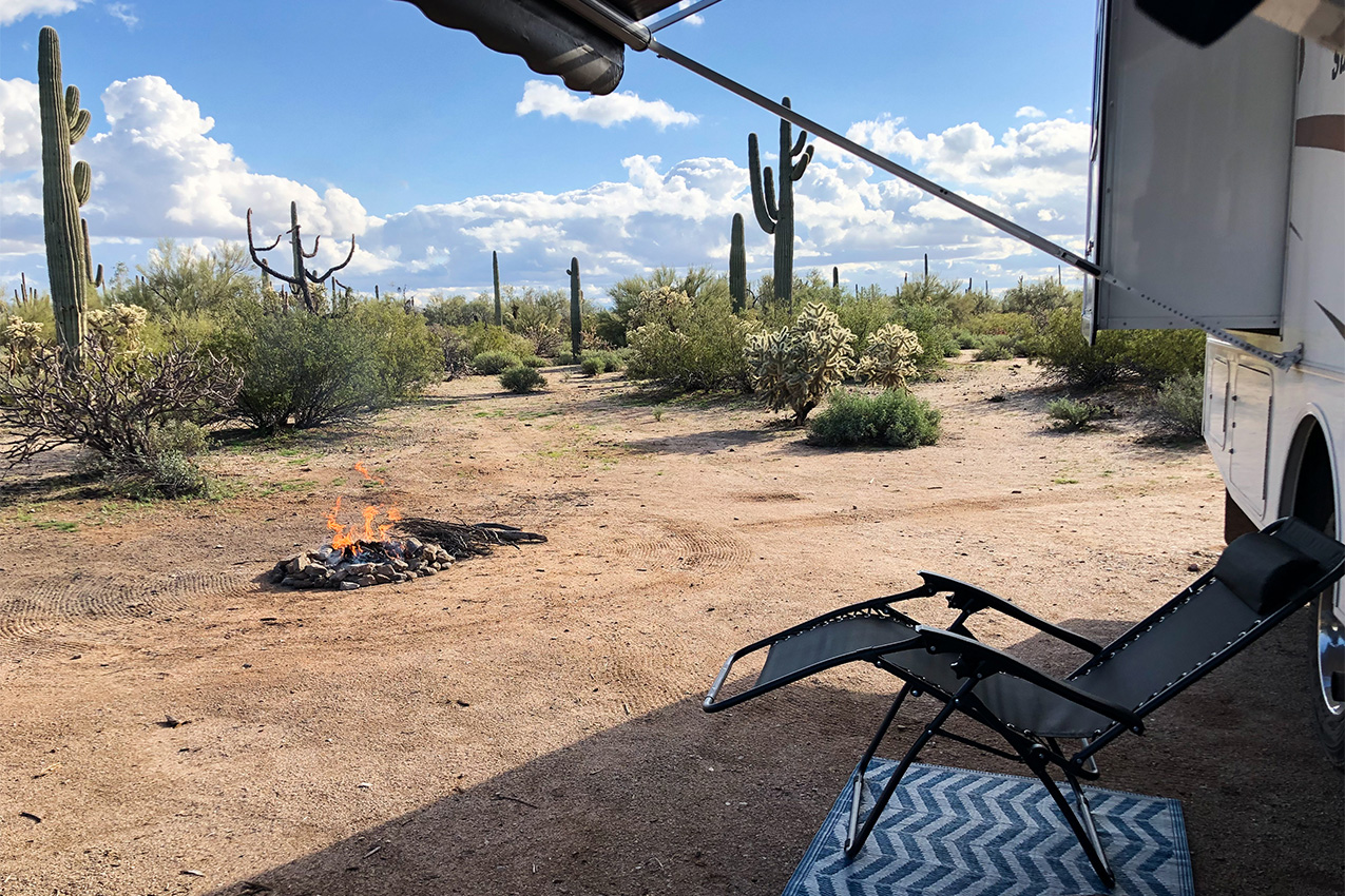 Empty camp recliner chair under shade of RV awning in the desert.
