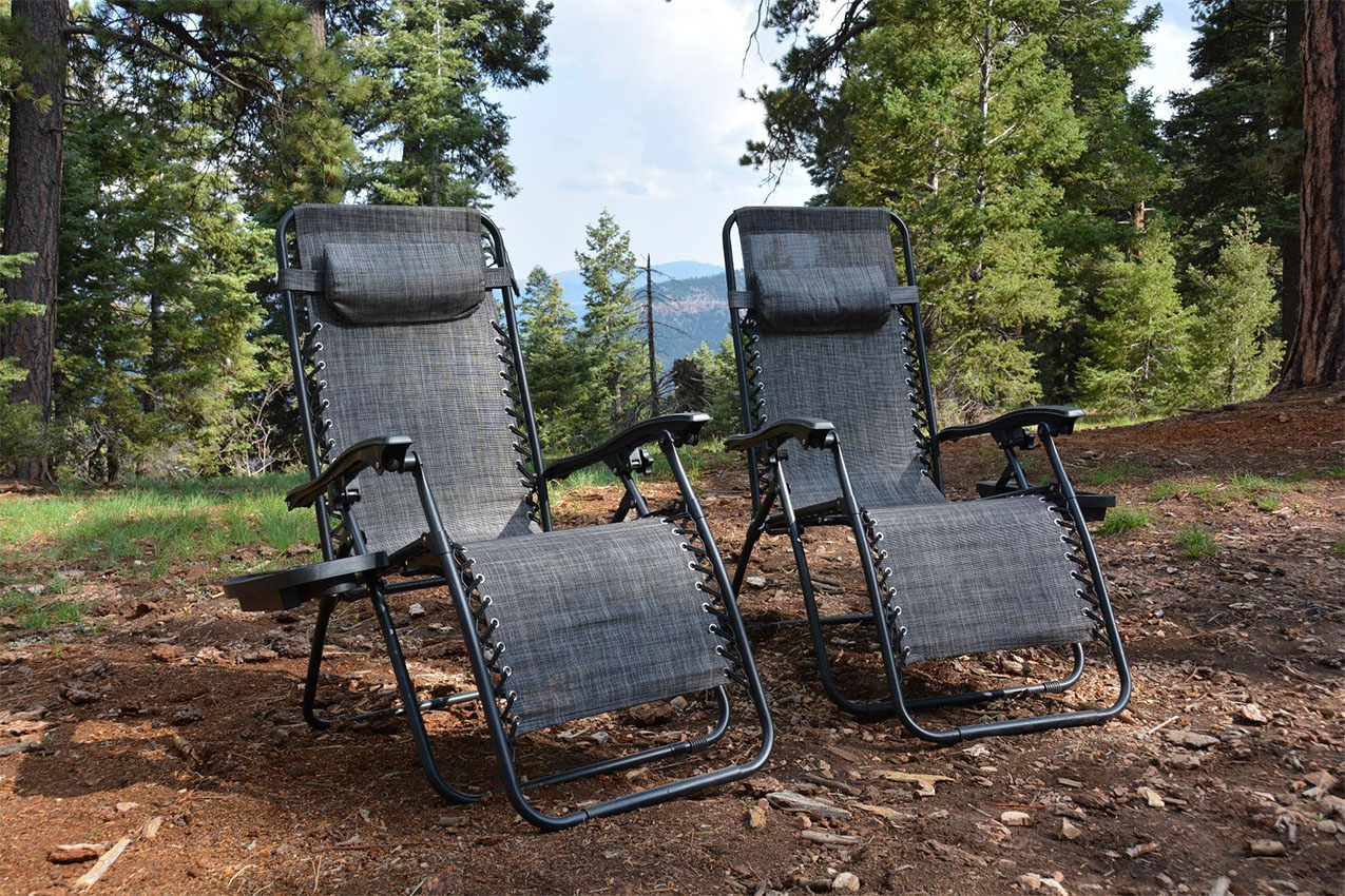 Two reclining camp chairs out in the woods.