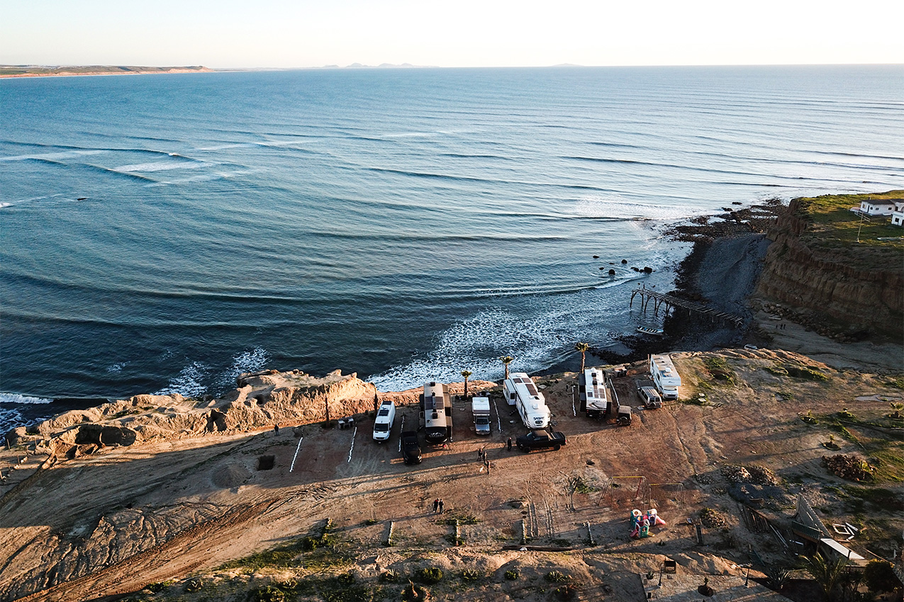 Aerial view of several RVs parked on the edge of a cliff overlooking the ocean.