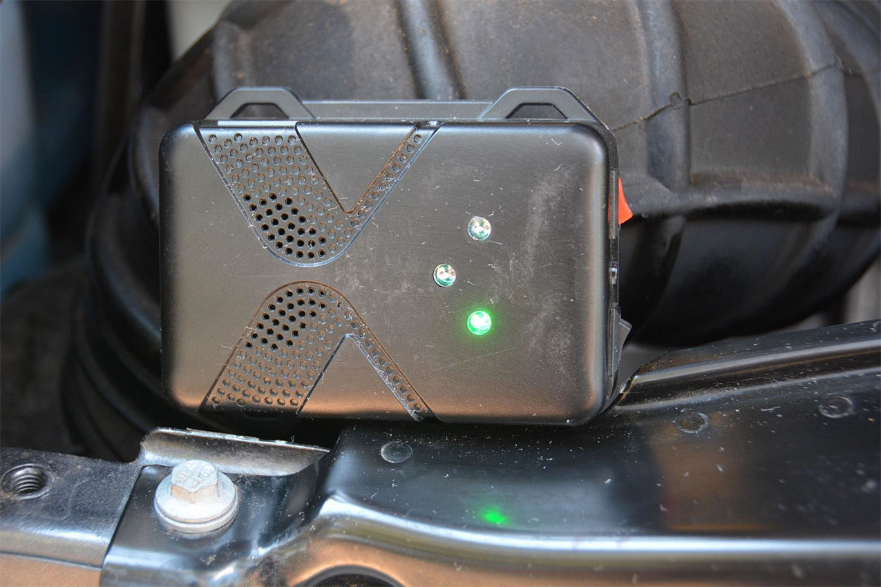 Black square rodent repeller with a green light on.