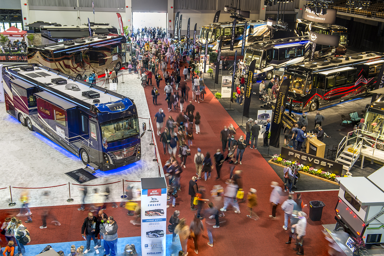 View from above of large class A and lots of people at an indoor RV expo.
