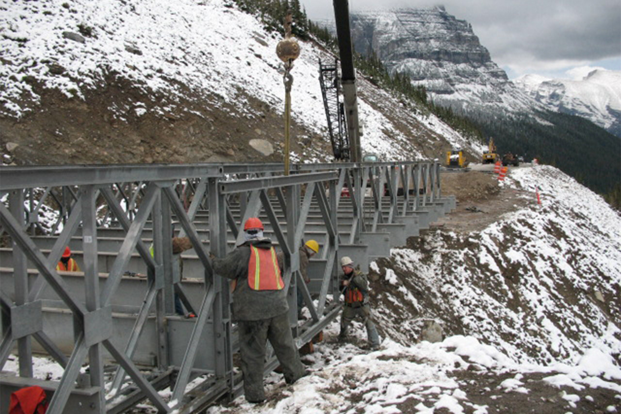Construction crew removing a bridge in the snow.