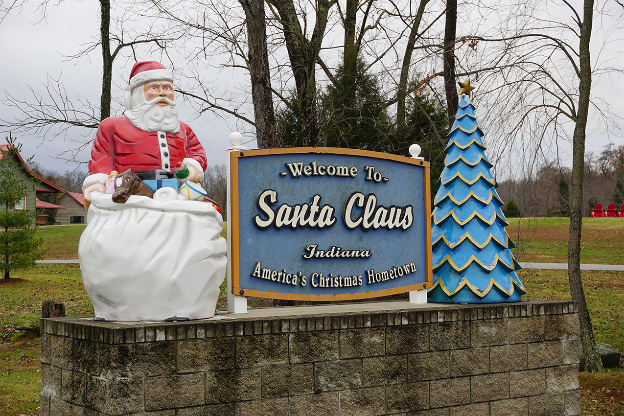 Town of Santa Claus welcome sign with Santa Claus and tree statue.