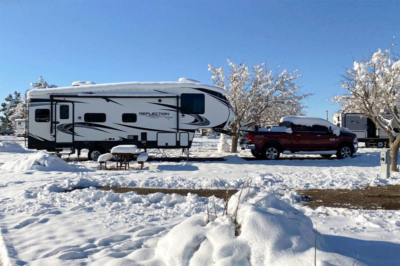 Fifth wheel and truck in an RV park covered in snow.