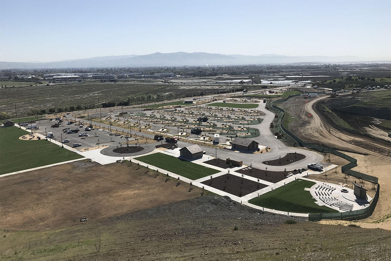 New RV park with empty sites surrounded by agricultural fields.