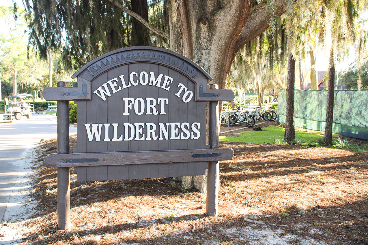 "Welcome to Fort Wilderness" wood sign under a large tree with hanging Spanish moss.