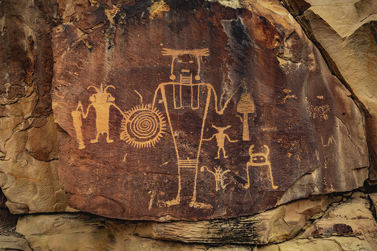 Ancient Warrior and anthropomorphic petroglyphs on a rock wall.