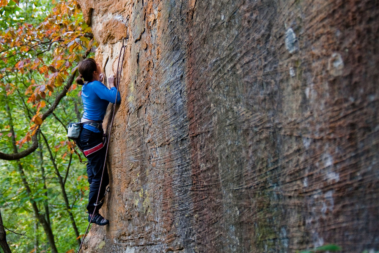 Woman climbing up a sandstone wall.
