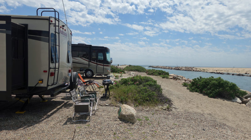 Two RVs parked on a beach next to the water