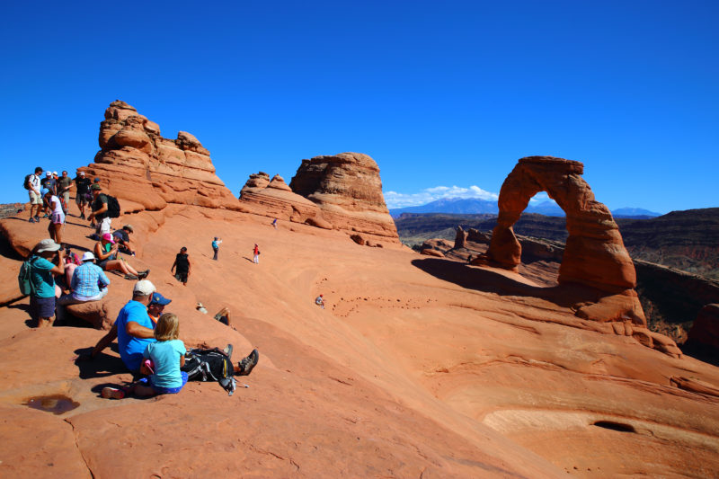 Groups of hikers sit at resting point amongst red rocks