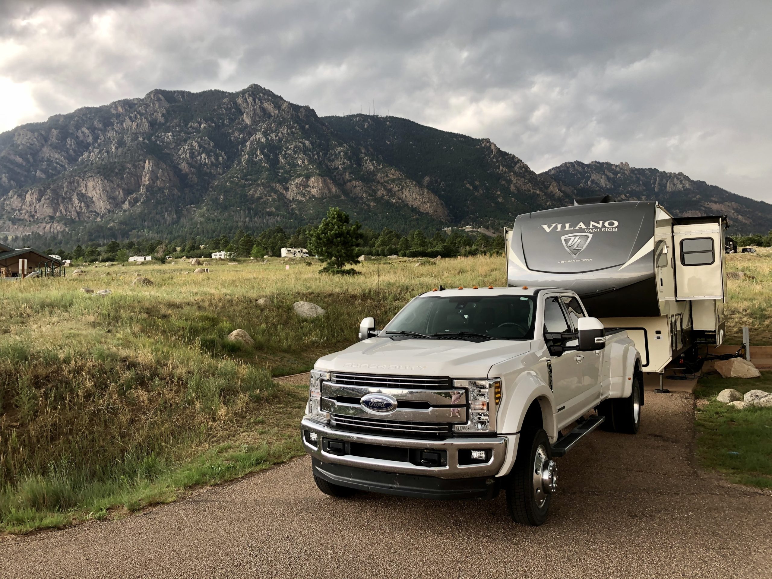 A Ford truck parked in front of a fifth wheel with its slides out against a mountain backdrop