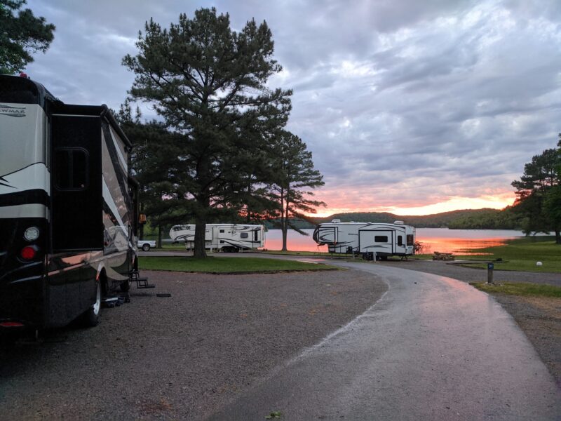 RVs parked next to lake at sunset