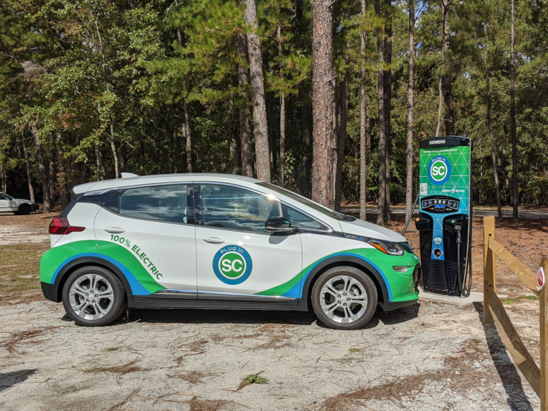 Electric vehicle at charging station in parking lot at wooded state park