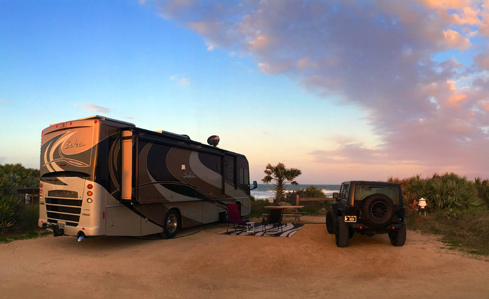 Motorhome parked at campsite at sunset next to beach