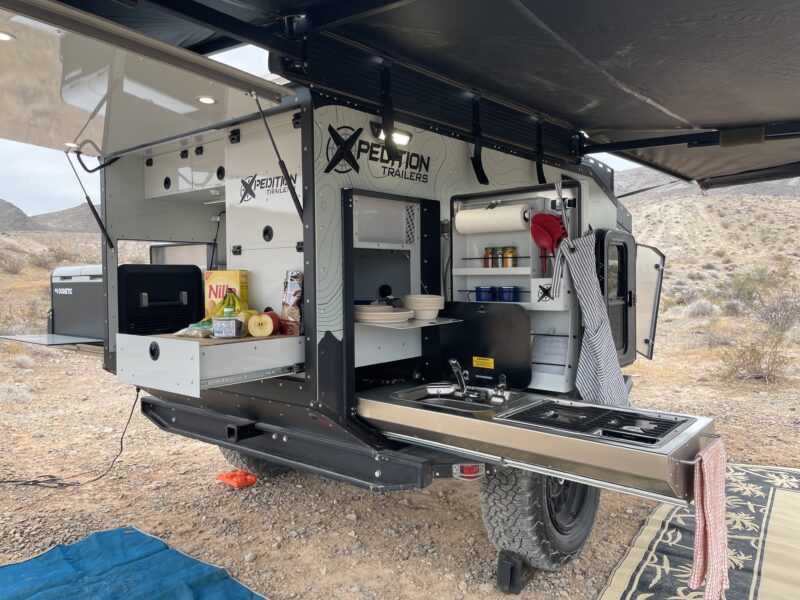 Overlanding RV with a tent on top and outdoor kitchen area