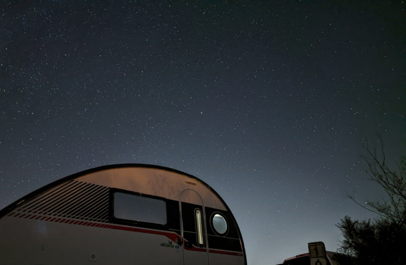 A tab trailer is parked underneath a dark night sky full of stars