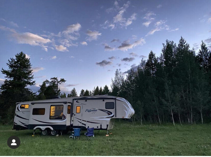 Large fifth wheel RV parked in a wooded area near Yellowstone National Park