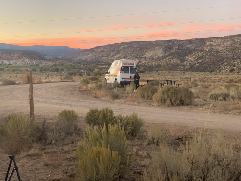 Van parked on sand road at sunset