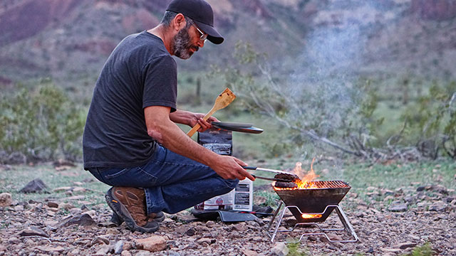 Man cooking over a foldable charcoal grill
