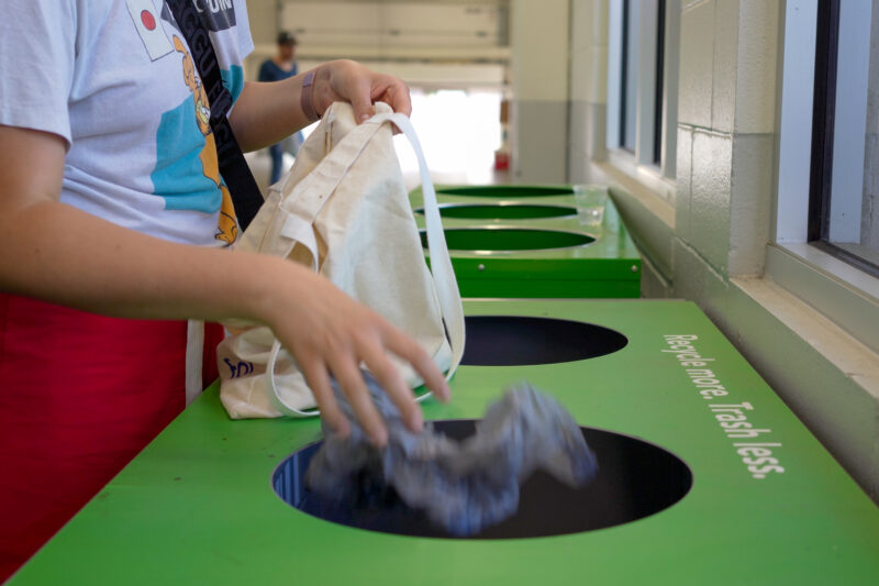 Throwing recycling into a green recycling bin